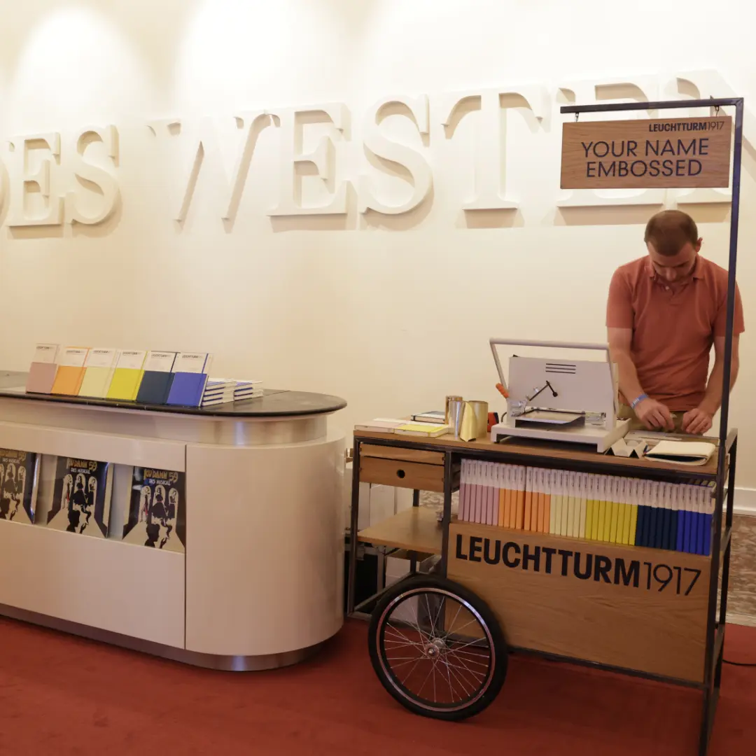 Leuchtturm1917 Präge-Service beim First Steps Award Trade fair stand with embossing station, LEUCHTTURM1917 notebooks and sign “Your Name Embossed”.
