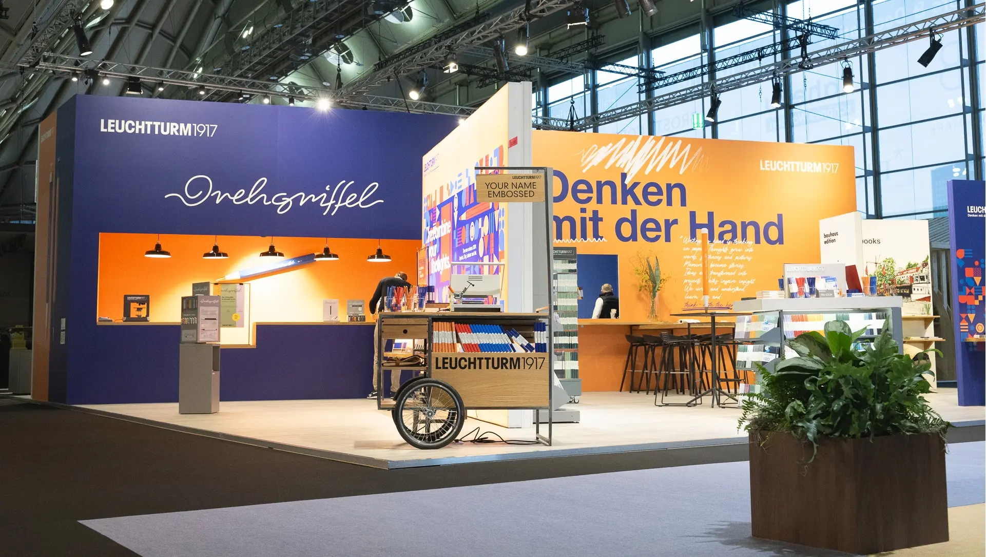 LEUCHTTURM1917 Messestand Ambiente 2024 LEUCHTTURM1917 trade fair booth with books and Drehgriffel, lettering “Drehgriffel”, “Denken mit der Hand”.