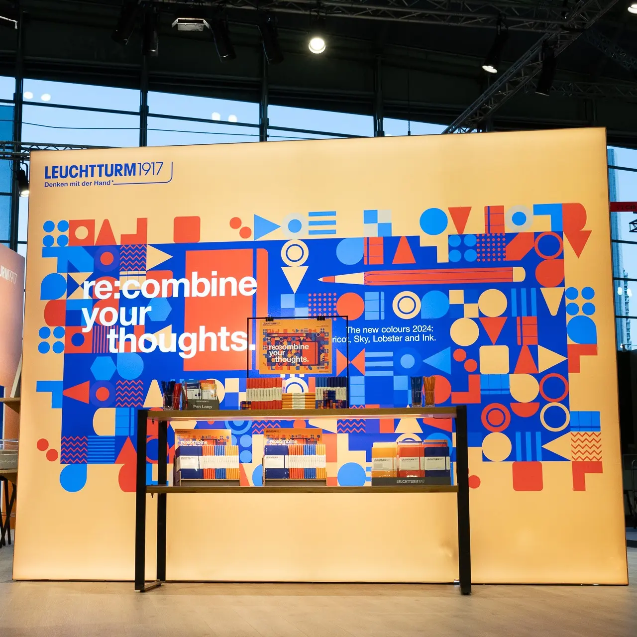LEUCHTTURM1917 Messestand Ambiente 2024 – New Colours Display. LEUCHTTURM1917 trade fair booth with colourful graphics, books and lettering “re-combine your thoughts.”.
