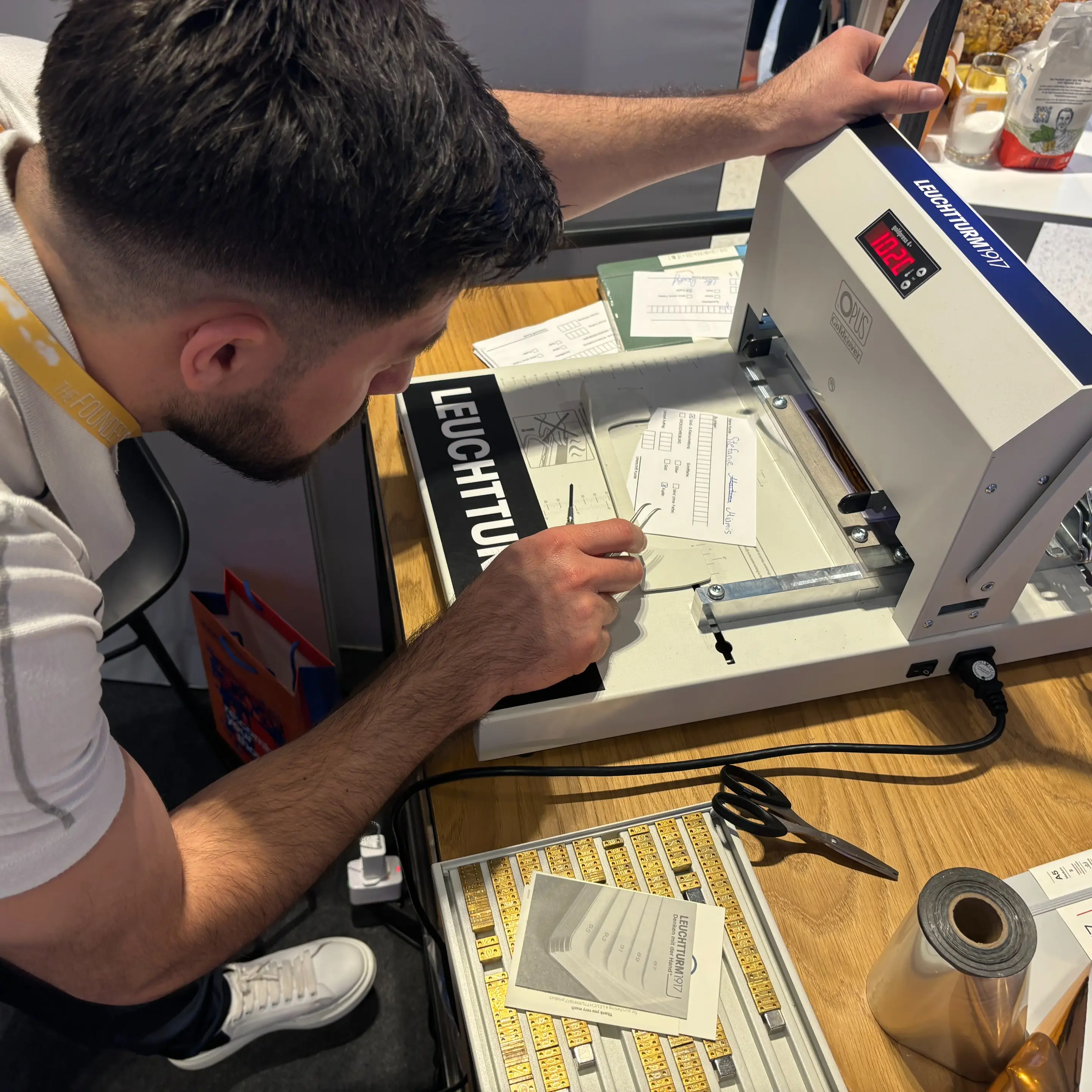 Momentaufnahme Leuchtturm1917 Live Prägung auf Founder Summit 2024 Messestand. Man embossing a notebook at an embossing station on a trade fair stand.