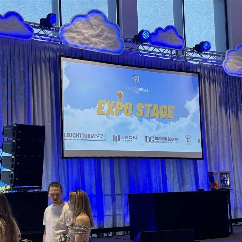 founder_1 Stage with screen, text “EXPO STAGE”, lighting and visitors in front.