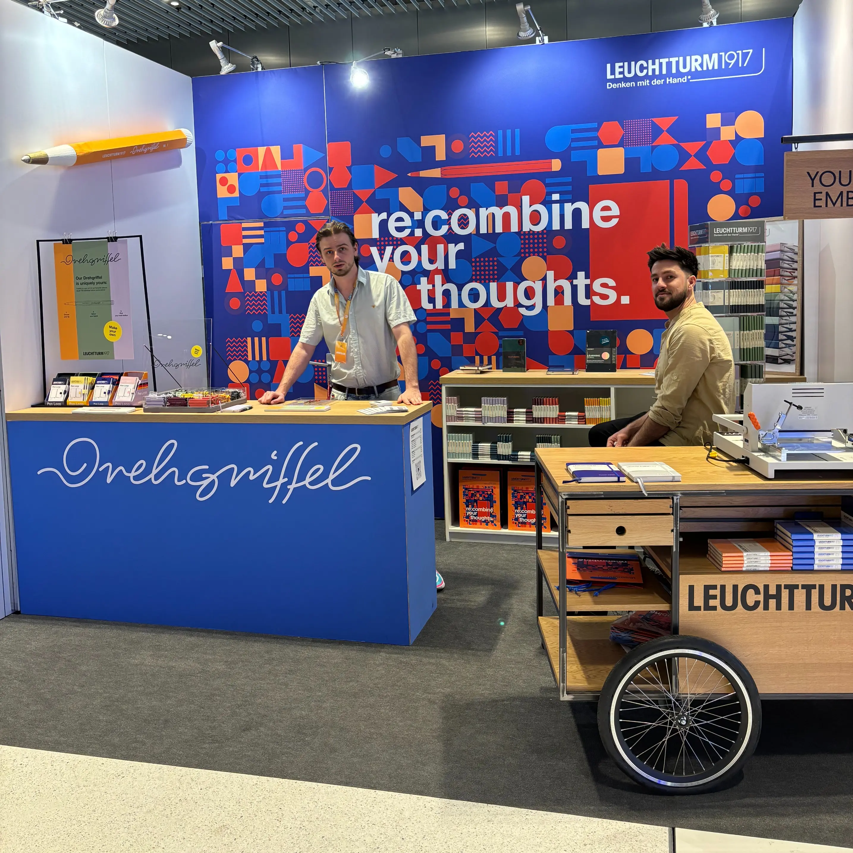 Leuchtturm1917 Messestand Founder Summit 2024. Two men at the Drehgriffel stand with embossing station.