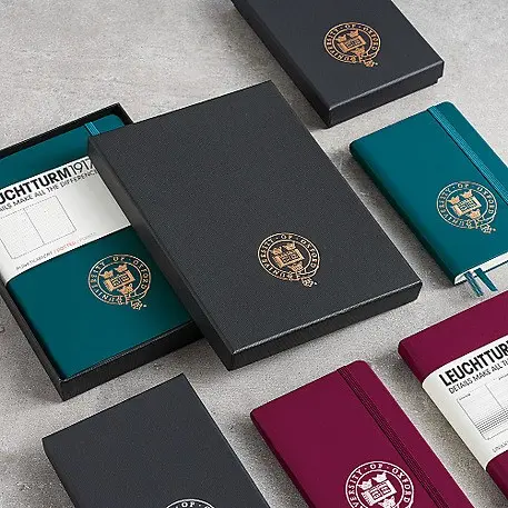 Green and burgundy notebooks with black boxes, gold and white embossing on box and notebook.