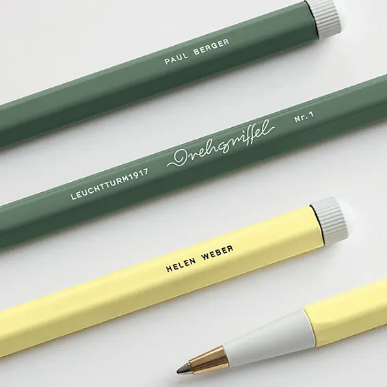 Zwei Drehgriffel Nr. 1 in Grün und Gelb mit eingravierten Beispielnamen sowie goldfarbener Spitze, dargestellt als Gravurbeispiel auf hellem Hintergrund.