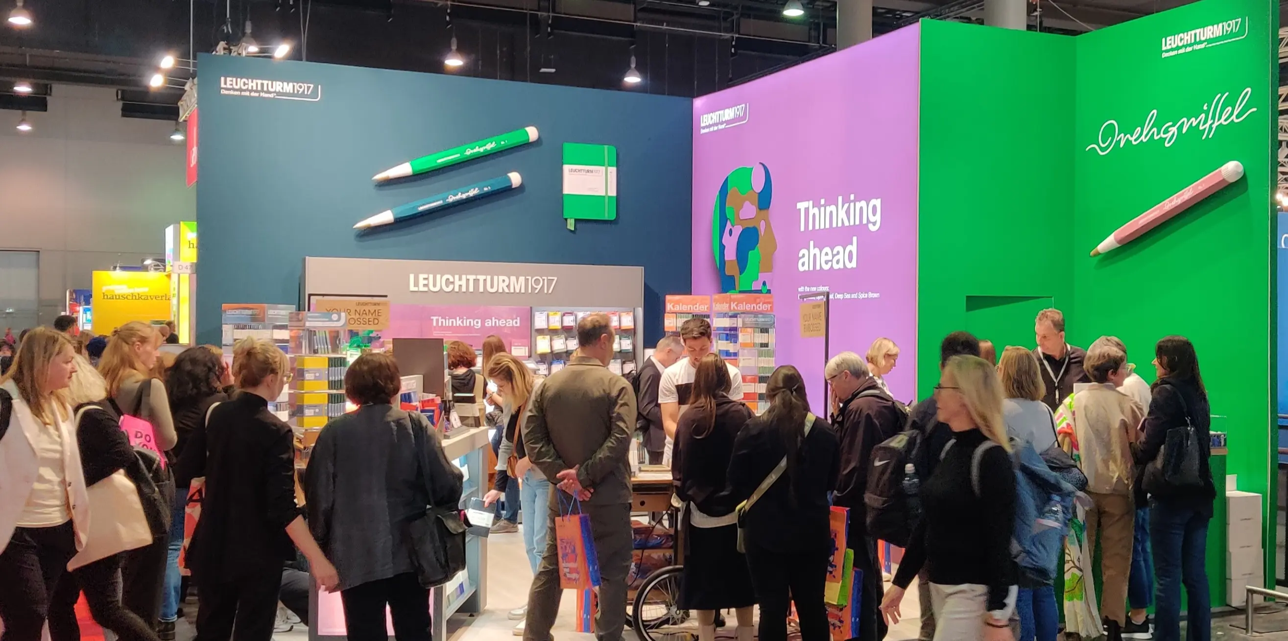 Gut besuchter Leuchtturm1917 Messestand auf der Frankfurter Buchmesse. LEUCHTTURM1917 trade fair stand with many visitors, shelves, embossing station and wall graphics.