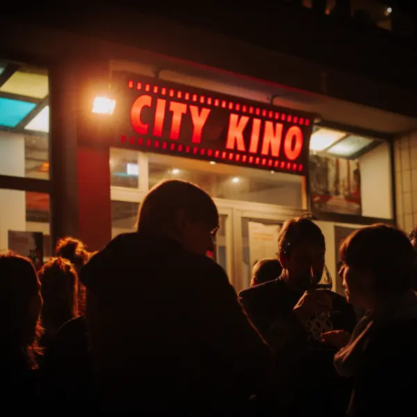 Einlass Human Rights Film Festival Berlin. People outside a cinema entrance at night, illuminated sign “CITY KINO”.