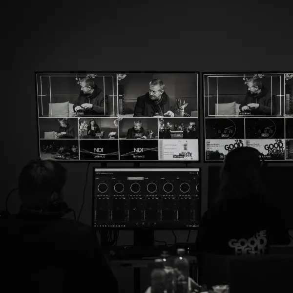 Regierraum Human Rights Film Festival Berlin. Black-and-white image of a control room with monitors and mixing desk, people manage live production.