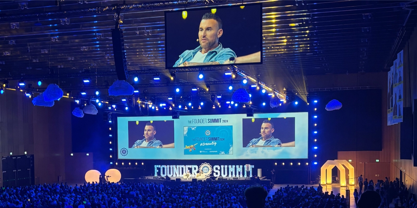 Founder Summit 2024 Bühnengespräch. Large hall with stage, screens and audience during a talk.