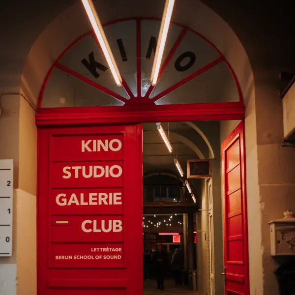 Red entrance with signage “KINO STUDIO GALERIE CLUB”, lit passageway.