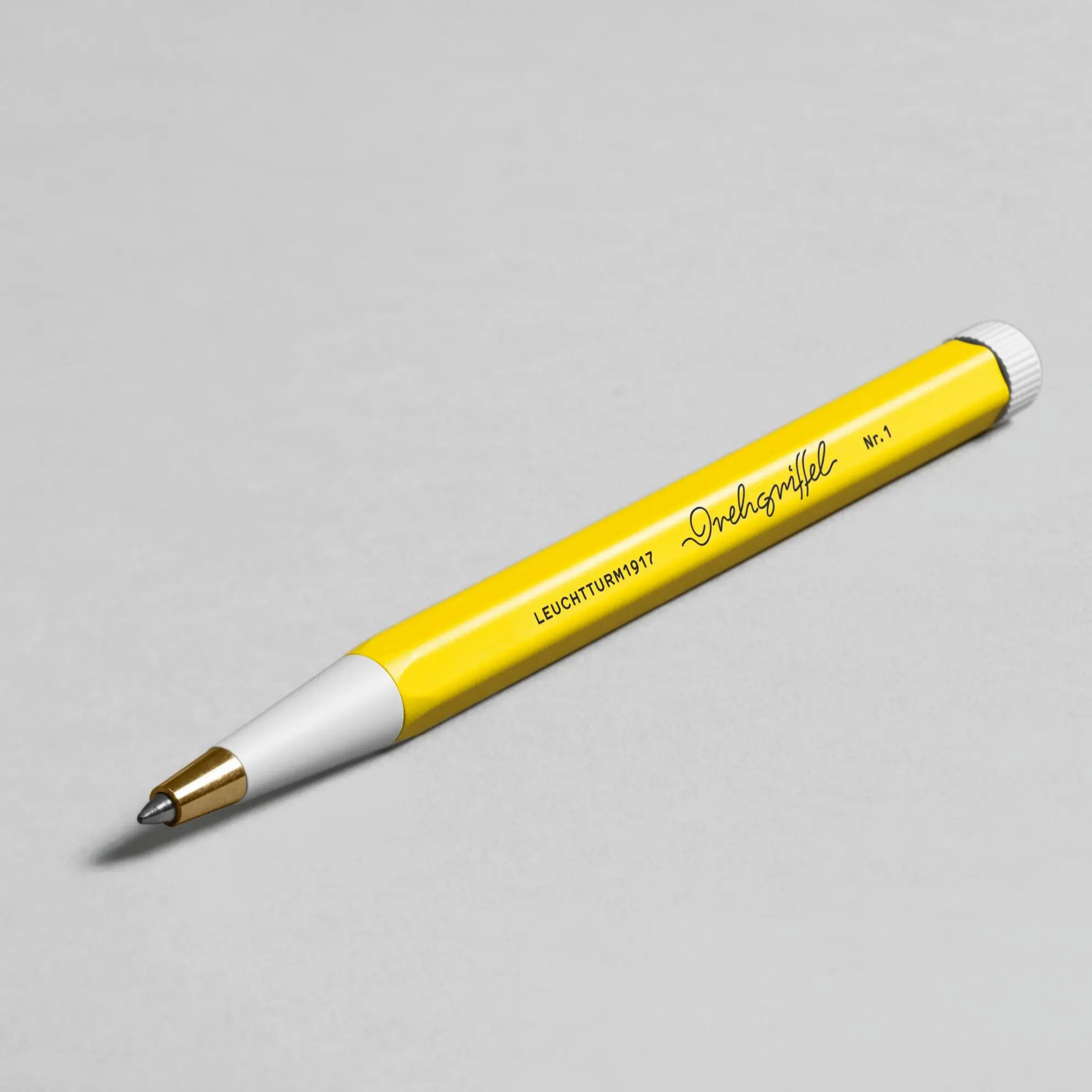 Drehgriffel Nr. 1 in der Farbe Zitrone mit weißem Griffstück und goldfarbener Spitze auf hellem Hintergrund.