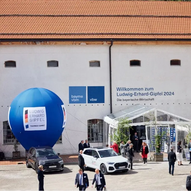 Außenansicht Ludwig-Erhard-Gipfel. Exterior view with balloon “LUDWIG ERHARD GIPFEL”, entrance and visitors outside building.