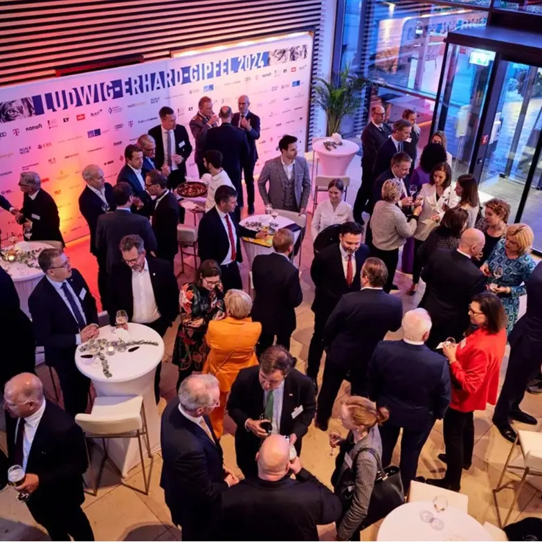 Ludwig-Erhard-Gipfel 2024 Empfang. Recepción con invitados bien vestidos frente al fondo «LUDWIG-ERHARD-GIPFEL 2024».