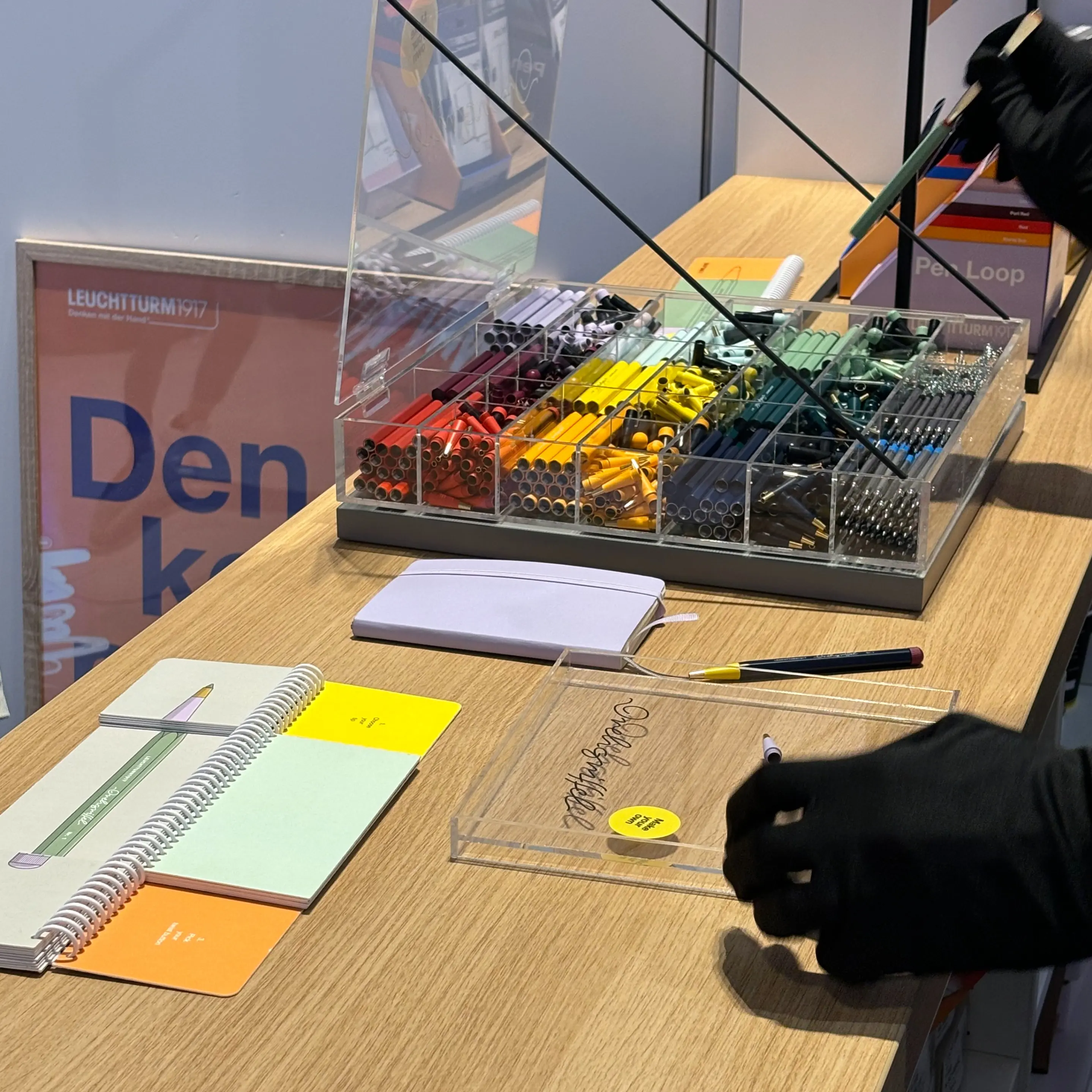 Leuchtturm1917 Drehgriffel auf dem Founder Summit 2024. Table with colorful Drehgriffel pens in a box, notebooks and hands selecting.