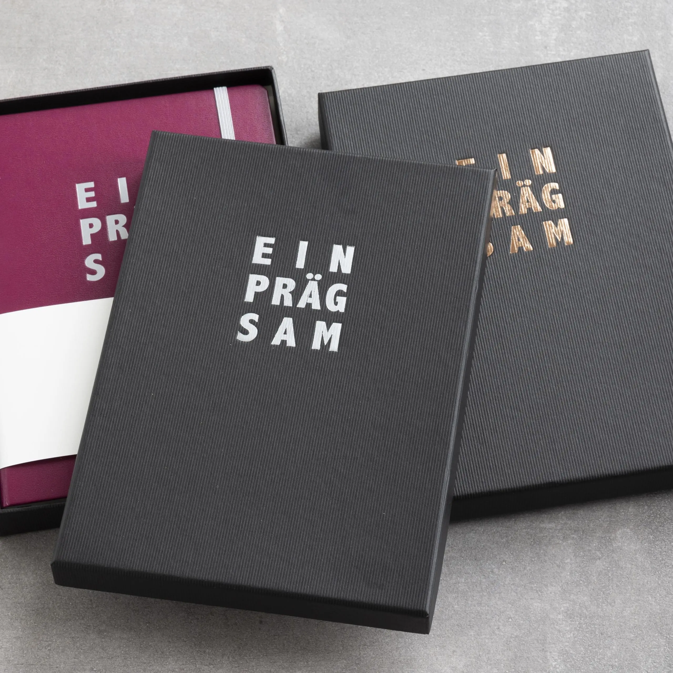 LEUCHTTURM1917 individuell gestaltetes Notizbuch in personalisierter Schachtel. Burgundy notebook in black box, embossing “EIN PRÄG SAM” on box and notebook.