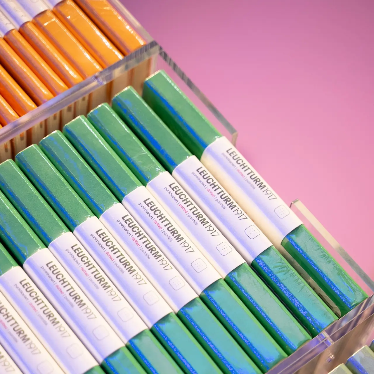 LEUCHTTURM1917 notebooks in green and orange, stacked in a display.