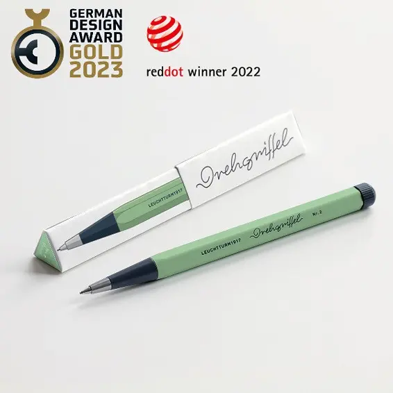Drehgriffel Nr. 2 in der Farbe Salbei mit dunkelgrauem Griffstück und silberner Spitze, daneben die passende Verpackung. Oben im Bild sind die Auszeichnungen German Design Award Gold 2023 und Red Dot Winner 2022 eingeblendet.