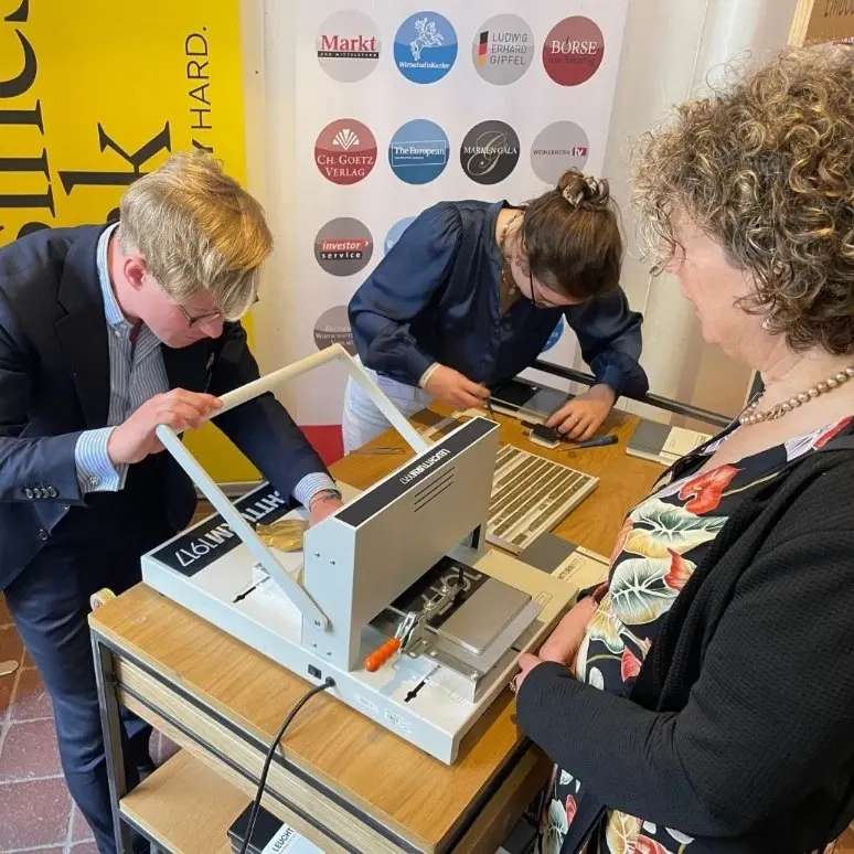 Leuchtturm1917 Notizbücher Prägeprozess. Personas graban libretas con una máquina en un stand.
