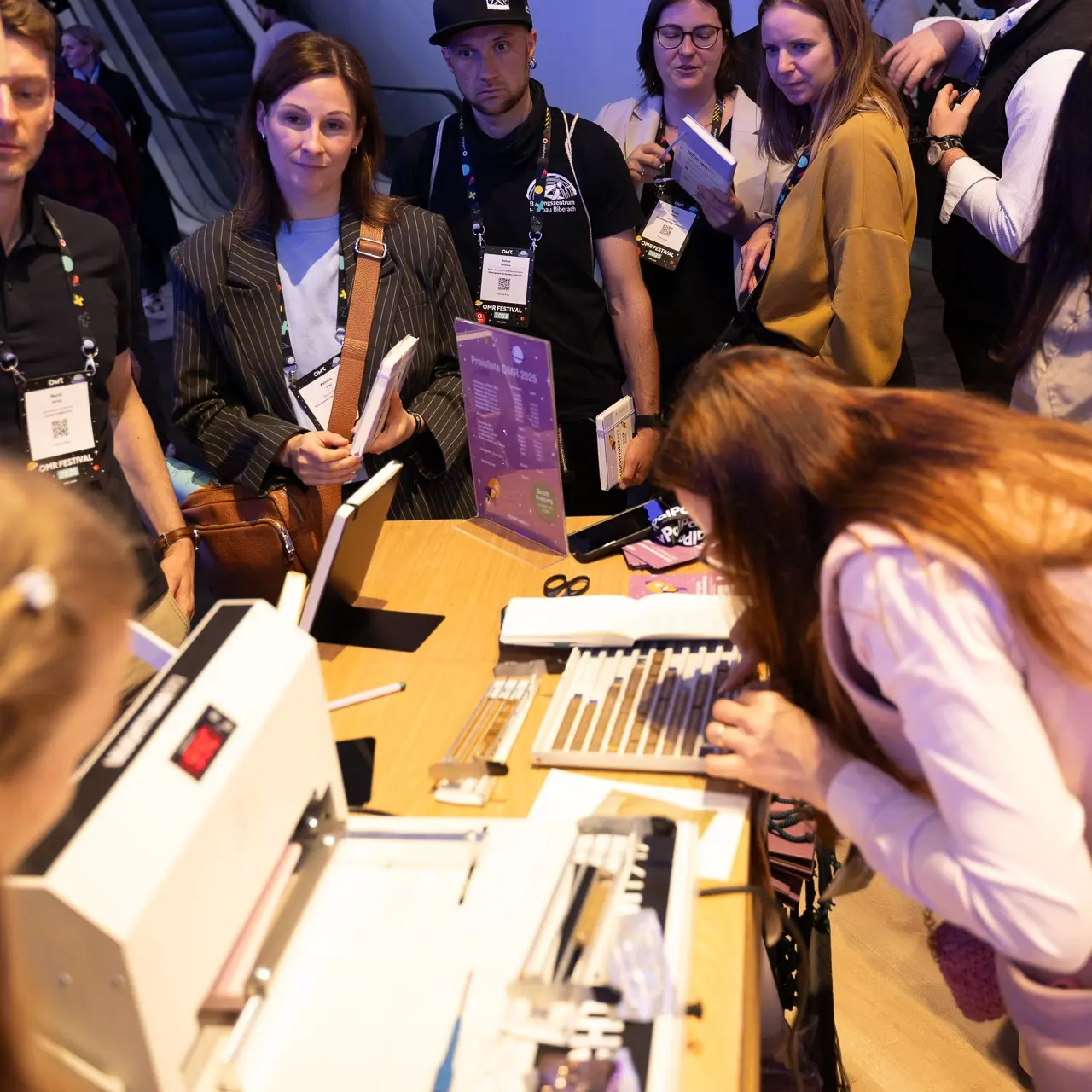 Leuchtturm1917 live Prägeevent auf der OMR 2025. People select letters for book embossing at an embossing station.